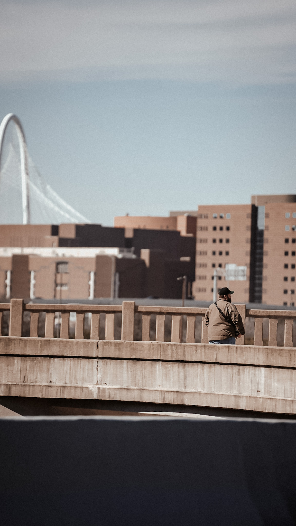 Figure on a bridge with the Dallas skyline